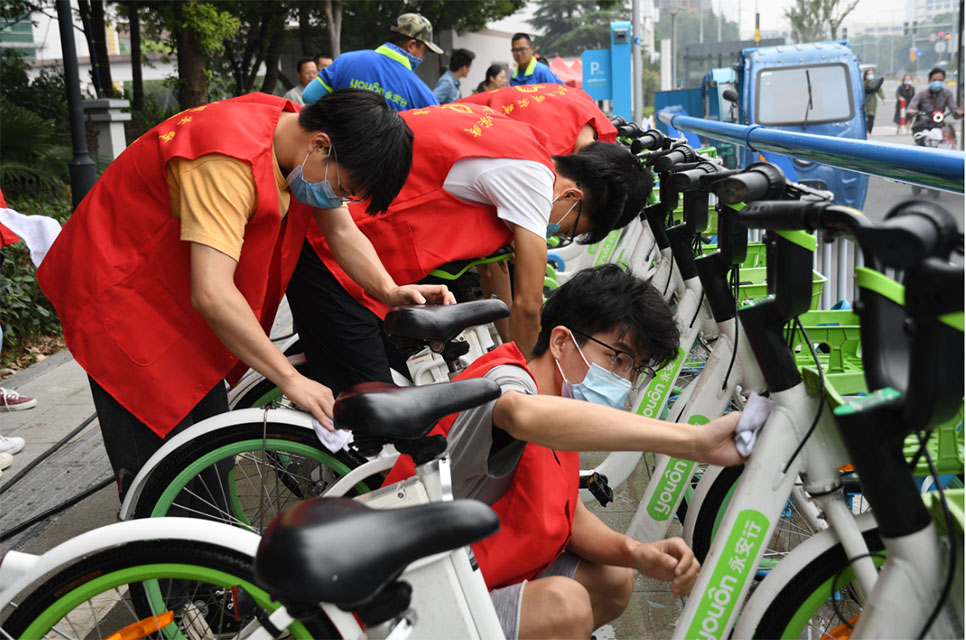 世界無(wú)車日，志愿者走上街頭擦亮共享助力車